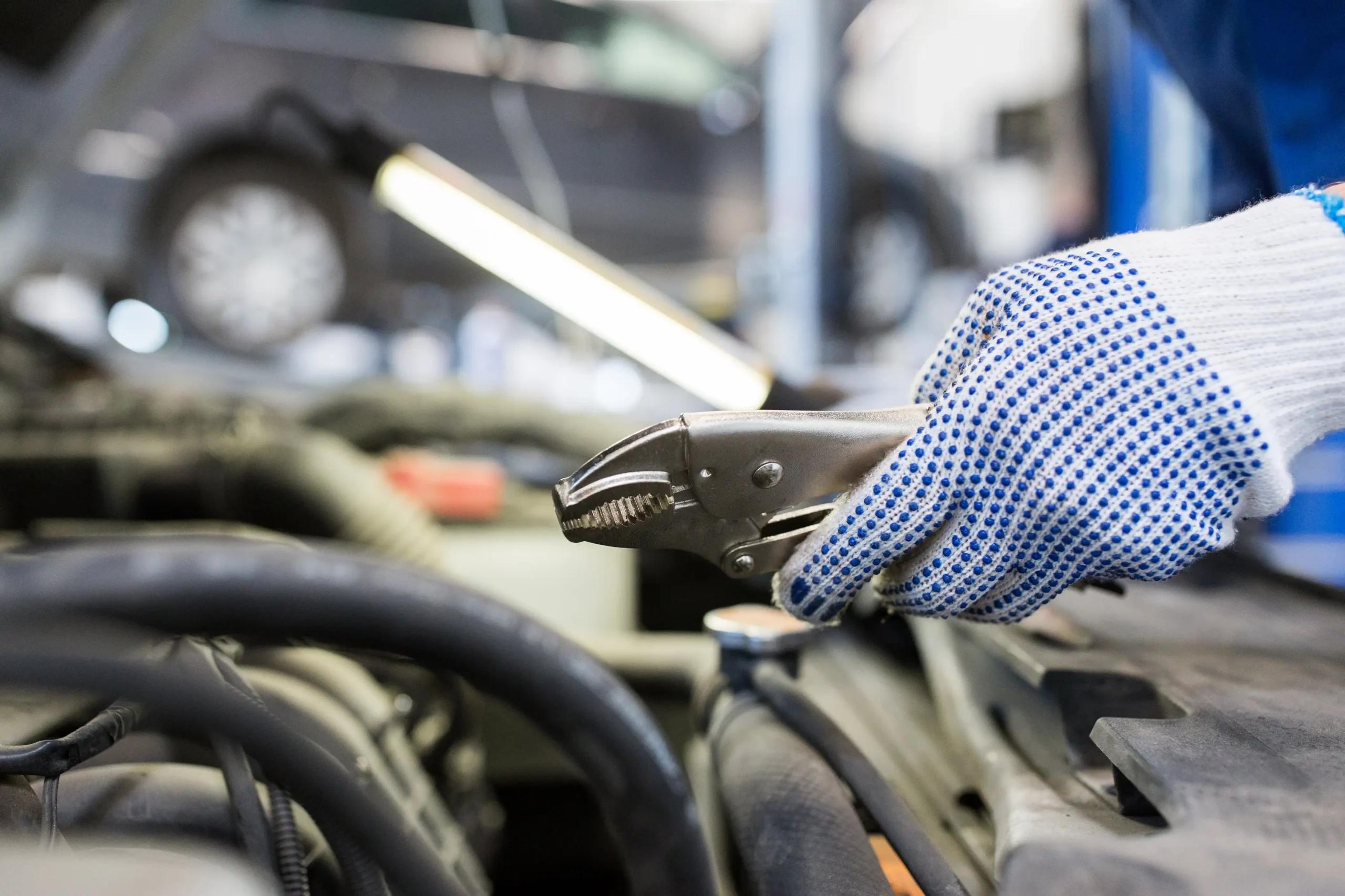 mechanic-man-with-pliers-repairing-car-at-workshop-2024-09-27-13-25-10-utc